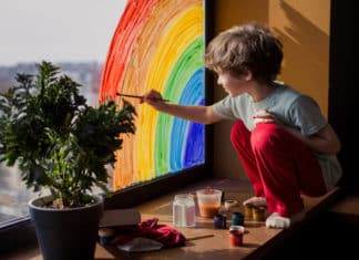 Criança pintando um arco-íris na janela.