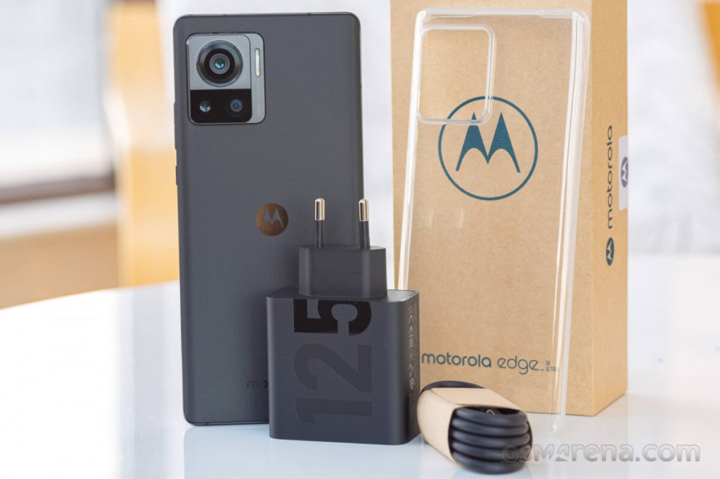 Motorola Edge 30 Ultra de cor preta junto aos seus acessórios presentes em cima de uma mesa. 
