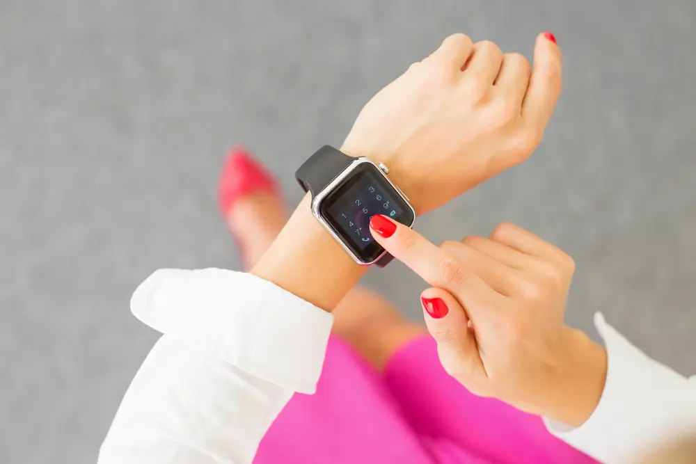 Mulher olhando para smartwatch monitorando sua saúde pelo relógio inteligente